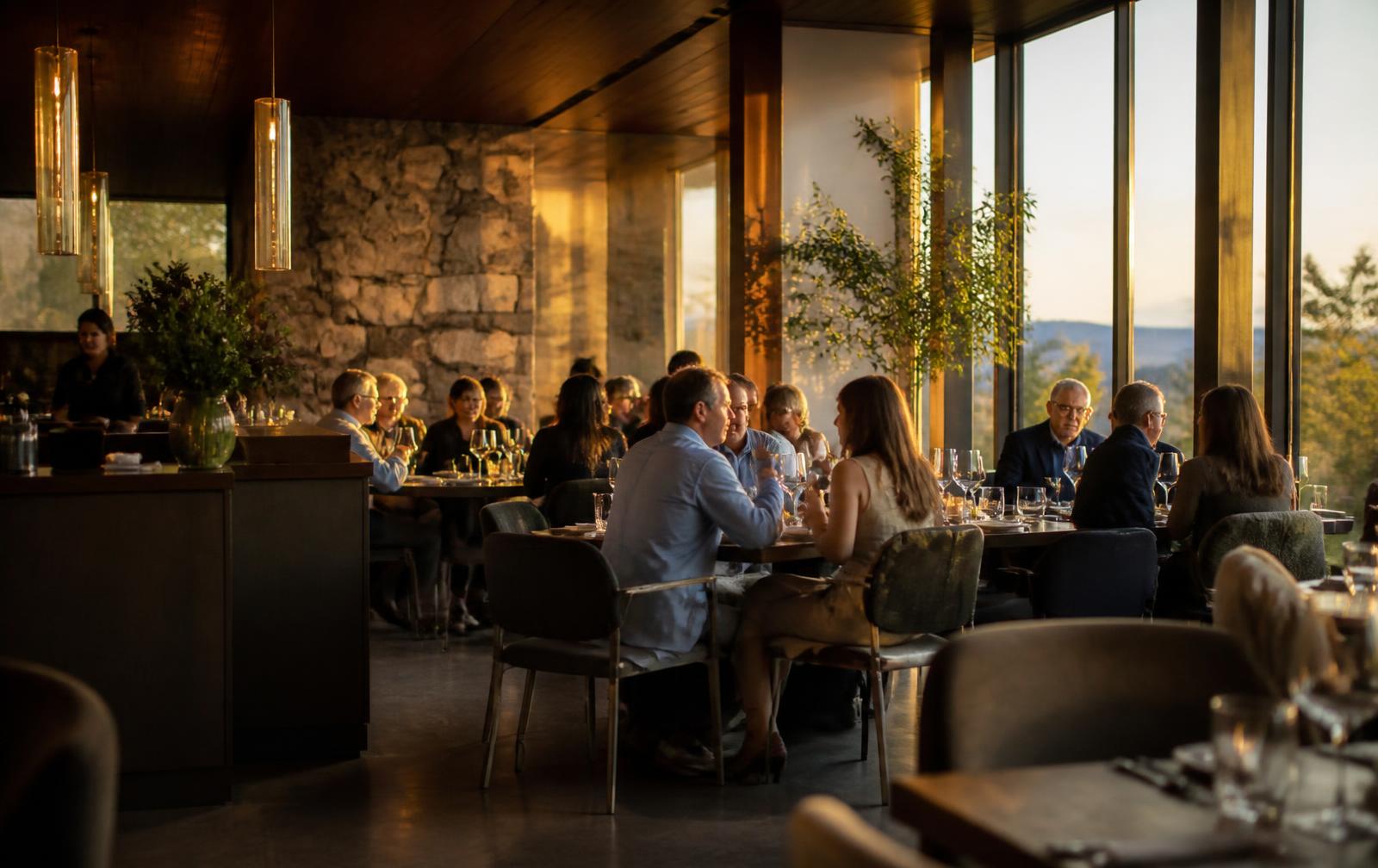 Guests dining in a warm modern restaurant at golden hour