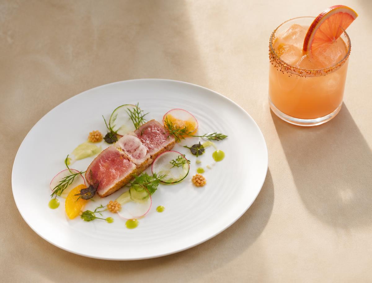 Plated modern dish next to a craft cocktail